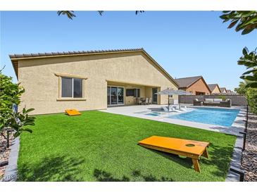Stunning backyard features a pool, spa, artificial turf, and a patio with outdoor furniture for relaxing and entertaining at 5321 Brayden Ct, Las Vegas, NV 89131