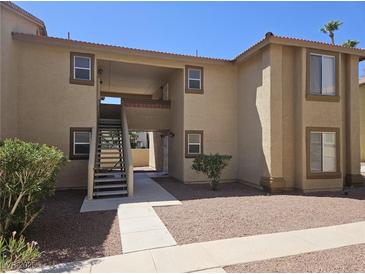 Tan two-story condo building with red rock landscaping, a staircase to the second floor, and an open entryway at 7300 Pirates Cove Rd # 2025, Las Vegas, NV 89145