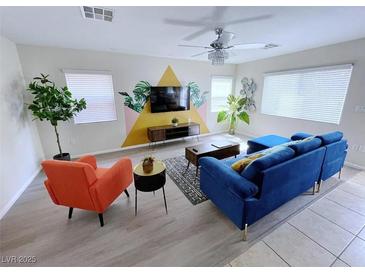 Stylish living room featuring a modern blue sofa, orange chair, and decorative accent wall at 7319 Burnt Umber St, Las Vegas, NV 89139