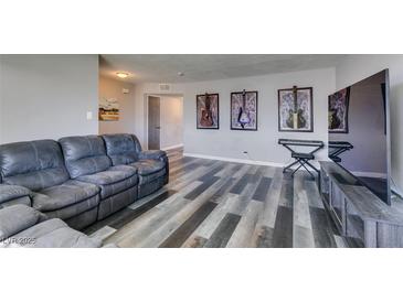 Inviting living room featuring wood-style flooring, a gray sofa, and vibrant guitar wall art at 100 Huntly Rd, Las Vegas, NV 89145