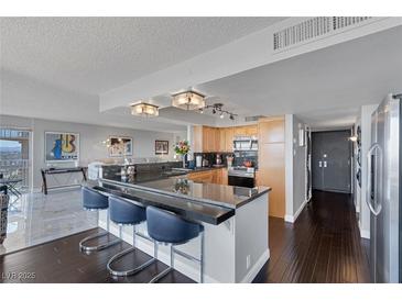 Open kitchen features granite counters, stainless steel appliances, and a breakfast bar with seating at 3111 Bel Air Dr # 16D, Las Vegas, NV 89109