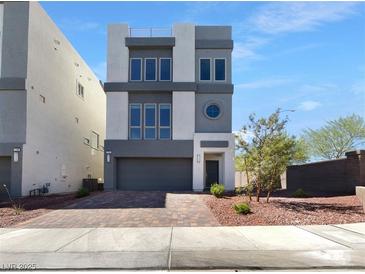 Beautiful, modern three-story home featuring a well-manicured front yard and gray color scheme at 7791 Misty Oaks Ave, Las Vegas, NV 89113