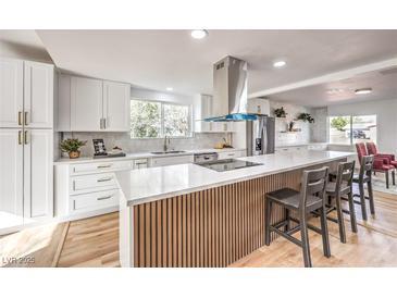 Bright kitchen featuring white cabinets, a large island with bar seating, and stainless steel appliances at 1731 Sherwin Ln, Las Vegas, NV 89156