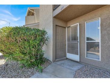 A tan two-story condo with gravel landscaping and a small decorative bush at the front door entrance at 433 Sellers Pl, Henderson, NV 89011