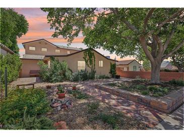 Charming home with a beautifully landscaped front yard featuring brickwork, lush greenery, and mature shade trees at 639 I Ave, Boulder City, NV 89005