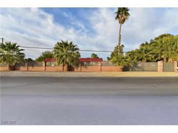 View of the property with palm trees, red roofing and a decorative, light brick perimeter fence at 2926 E Eldorado Ln, Las Vegas, NV 89120