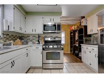 Well-lit kitchen features white cabinets, stainless steel appliances, and stone countertops at 3928 Edgemoor Way, Las Vegas, NV 89121