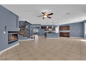Bright, open-concept living room with a fireplace, tile floors, and a staircase leading to the upper level at 4063 Lower Saxon Ave, North Las Vegas, NV 89085