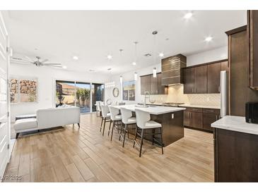 A spacious kitchen with a large island, modern appliances, and stylish pendant lighting overlooking a living room at 52 Reverie Heights Ave, Henderson, NV 89011