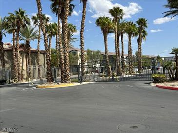 View of the gated community entrance featuring lush palm trees and well-maintained landscaping at 8000 Badura Ave # 1168, Las Vegas, NV 89113