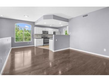Bright living room featuring wood floors and an open-concept design leading to the kitchen at 10211 Red Pueblo Pl # 203, Las Vegas, NV 89144
