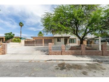 Charming single-story home featuring a two-car garage, gated entry, and mature tree at 1806 Renada Cir, North Las Vegas, NV 89030