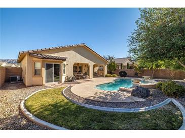 Inviting backyard pool with landscaped rock feature and covered patio, perfect for outdoor relaxation and entertaining at 4937 Semifonte Dr, Pahrump, NV 89061