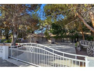 Charming single-story home with a decorative white fence, mature trees, and stone accents at 5159 N Monte Cristo Way, Las Vegas, NV 89149