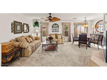 Inviting living room featuring plush sofas, a ceiling fan, and elegant decor with an adjacent dining area at 9522 Arrowhead Falls Ct, Las Vegas, NV 89148