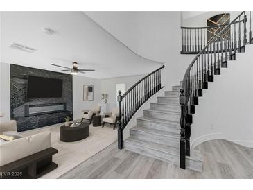 Bright living room showcasing a marble fireplace, sleek ceiling fan, and a stylish staircase with black railing at 9541 Summersweet Ct, Las Vegas, NV 89123