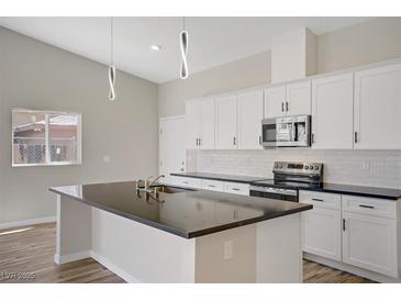 Bright kitchen features a dark countertop island and stainless steel appliances against white cabinets at 2130 Revere St, North Las Vegas, NV 89030