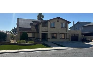 Two-story home featuring solar panels, a two-car garage, green front yard, and a tan exterior at 4356 Sabadell St, Las Vegas, NV 89121