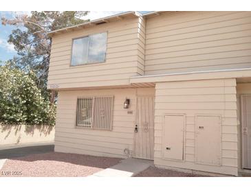 Beige two-story townhome with decorative front door and grated window at 5086 Mountain Vista St, Las Vegas, NV 89120