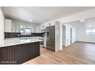 Modern kitchen features stainless steel appliances, white cabinetry, quartz countertops, and a stylish backsplash and wood flooring at 6308 Lawton Ave, Las Vegas, NV 89107