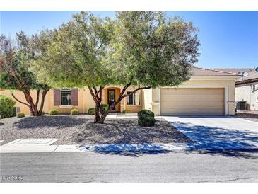 Charming single-story home featuring a desert landscape, mature trees, and an attached two-car garage at 2183 Waterton Rivers Dr, Henderson, NV 89044