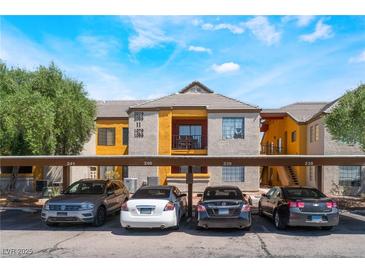 Apartment complex featuring covered parking, yellow exterior accents, and well-maintained landscaping at 2700 N Rainbow Blvd # 1080, Las Vegas, NV 89108