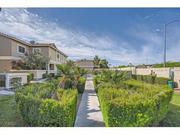 Landscaped walkway leading to a community with lush greenery and blue skies at 3253 Mystic Ridge Ct, Las Vegas, NV 89129