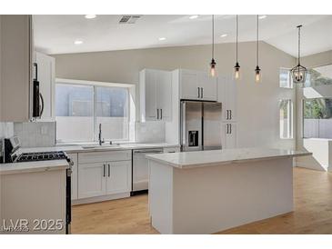 Bright, updated kitchen features stainless appliances, a kitchen island with white cabinets, and generous natural light at 4010 Herblinda Ln, North Las Vegas, NV 89032