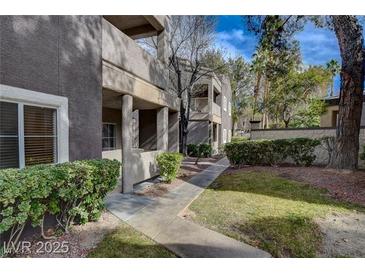 Exterior view of a multi-story condo building with well-maintained landscaping, bushes, and sidewalk at 5250 S Rainbow Blvd # 2183, Las Vegas, NV 89118