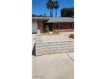Charming single-story home featuring a gray roof, red brick, and desert landscaping at 2700 Osborne Ln, Henderson, NV 89014