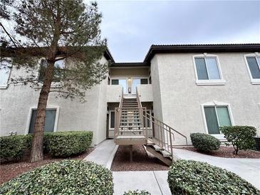 A building exterior featuring beige siding, well maintained landscaping and a stairway leading to the second floor at 3354 Indian Shadow St # 203, Las Vegas, NV 89129