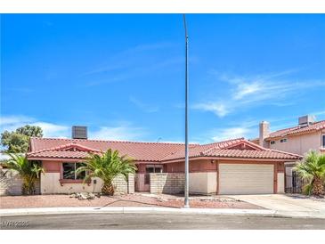 Charming single-story home featuring a tile roof, palm trees, and an attached two-car garage at 3434 Toquima Cir, Las Vegas, NV 89120
