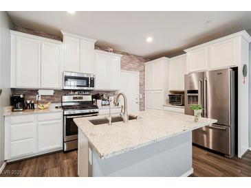 Beautiful kitchen features white cabinetry, stainless steel appliances, an island, and brick-style backsplash at 6228 Haiku Stairs St, Las Vegas, NV 89148