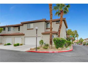 Charming townhome featuring a stucco exterior, red tile roof, two-car garage, and desert landscaping at 8012 Desire Ave, Las Vegas, NV 89128