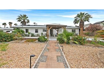 Charming single-story home with desert landscaping, palm trees, and a covered patio, perfect for outdoor relaxation at 1595 E Camero Ave, Las Vegas, NV 89123