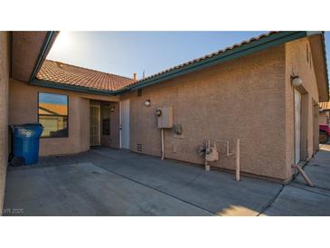 Tan stucco exterior with concrete courtyard and tile roofing, creating a unique outdoor living space at 305 Crosswind Way, Las Vegas, NV 89145