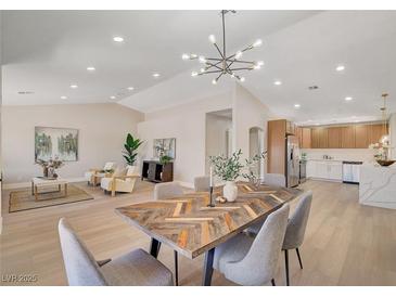 Bright, open dining area with stylish light fixture and access to a modern kitchen at 7805 Leavorite Dr, Las Vegas, NV 89128
