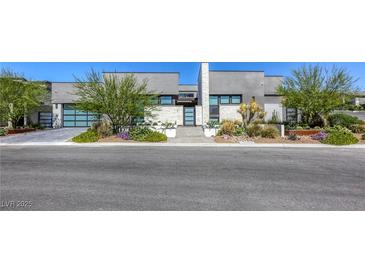 Modern home showcasing sleek design, desert landscaping, stone accents, and a glass garage door at 787 Keyland St, Las Vegas, NV 89138