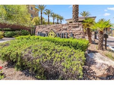Welcoming stone community sign surrounded by lush landscaping and palm trees under a bright blue sky at 9125 Las Manaitas Ave # 302, Las Vegas, NV 89144
