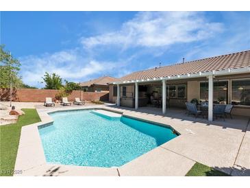 Resort-style backyard featuring a sparkling pool, lounge chairs and covered patio with comfortable seating area at 9362 Wilderness Glen Ave, Las Vegas, NV 89178