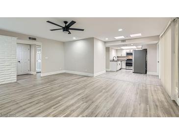 Open living space featuring modern gray wood floors and bright lighting with kitchen area view at 3310 Heritage Pl, Las Vegas, NV 89121