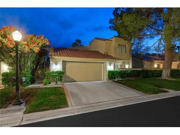 Charming two-story home with a well-maintained lawn, driveway, and two-car garage at dusk at 5125 Turnberry Ln, Las Vegas, NV 89113