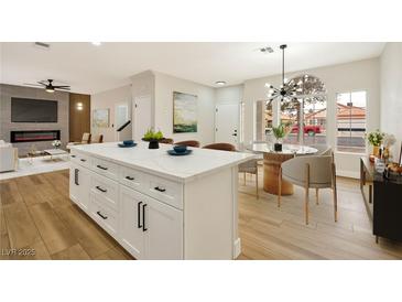 Bright, open kitchen featuring an island with white cabinets and a modern light fixture above the dining area at 6388 Canyon Dawn Ave, Las Vegas, NV 89108