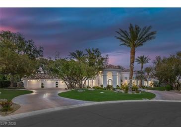 Stunning exterior of the home featuring a circular driveway, multiple garages, palm trees, and beautiful landscaping at 8130 Cassian Ct, Las Vegas, NV 89129