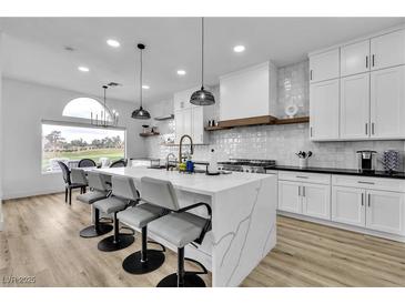 Modern white kitchen featuring an island with waterfall countertop and pendant lighting at 9513 Villa Ridge Dr, Las Vegas, NV 89134