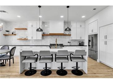 A modern kitchen with white cabinets, an island with bar stools, and stainless steel appliances at 9513 Villa Ridge Dr, Las Vegas, NV 89134