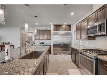 A stylish kitchen with granite countertops, stainless steel appliances, and sleek wood-look flooring at 6790 Tangled Vines Ave, Las Vegas, NV 89139
