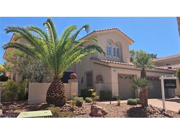 Two-story home featuring a neutral color palette, well-manicured landscaping, and desert-friendly plants and decorative rocks at 8205 Taos Paseo Ave, Las Vegas, NV 89128