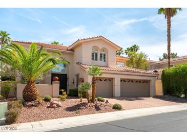 Elegant two-story home with a three-car garage and desert landscaping featuring palm trees at 8205 Taos Paseo Ave, Las Vegas, NV 89128