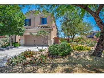 Charming two-story home with a well-manicured front yard, lush trees, and a spacious driveway leading to a two-car garage at 10692 Tulip Valley Rd, Las Vegas, NV 89179